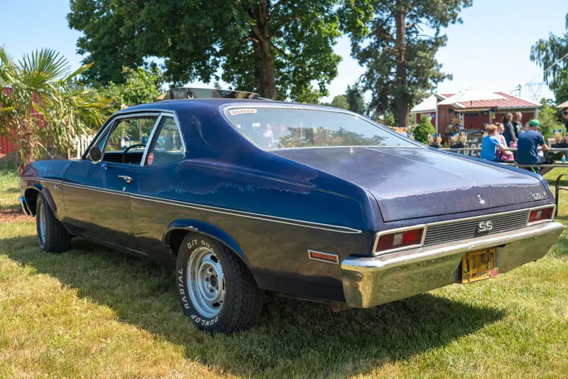 Rear three-quarter view of the dark blue coupe, chrome bumper and tail panel catching the light
