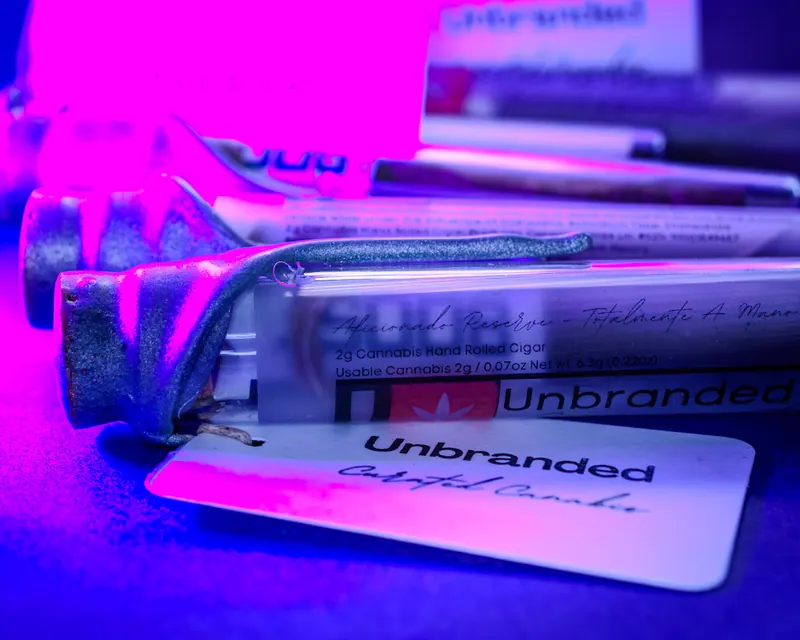 Product tubes with metal end caps lit in blue and magenta, brand card angled behind