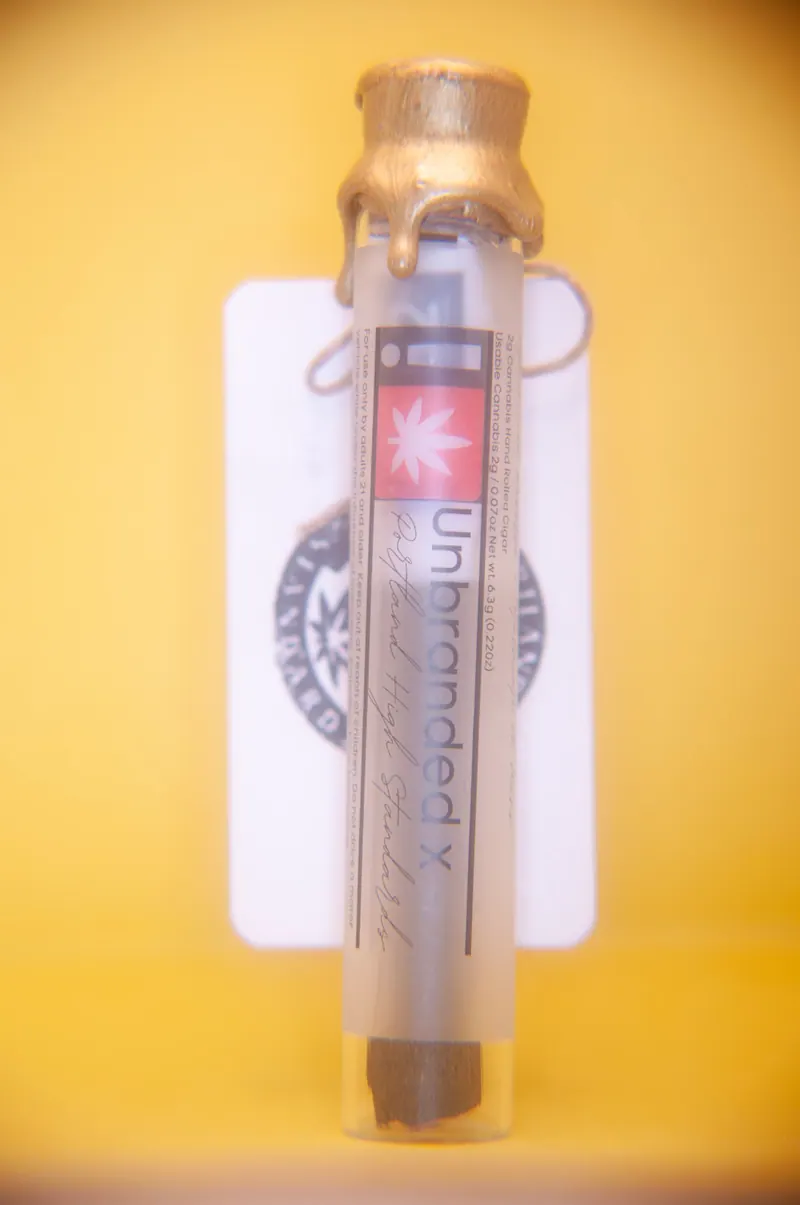 Product tube standing upright with a gold wax seal against a flat yellow background