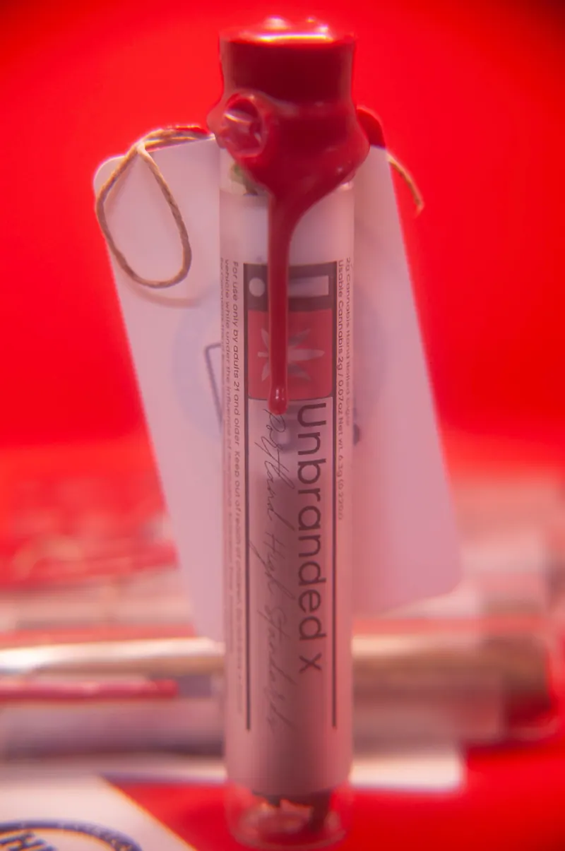 Product tube standing upright with a red wax seal against a saturated red background