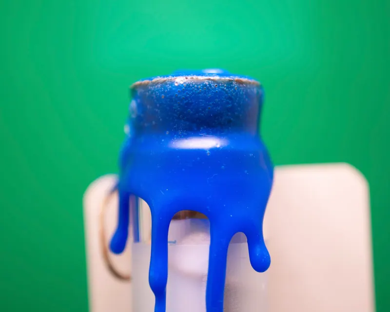 Blue wax seal running in thick drips down a white card on a green background