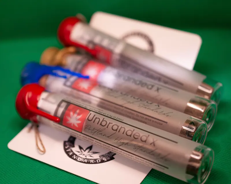 Stacked product tubes with blue and red seals laid across a brand card on green